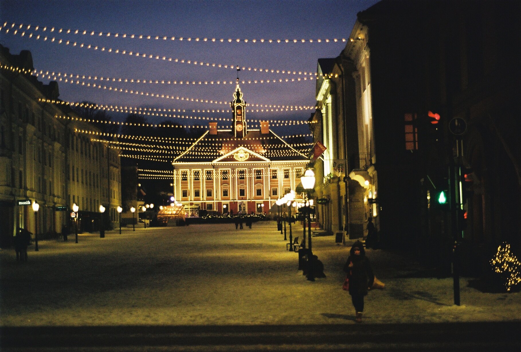 Tartu's Town Hall Square lit up at night with strings of lights over the snow-covered square.